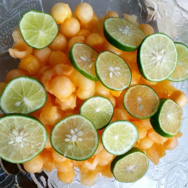 Siapkan mangkuk, masukkan blewah lalu iris-iris jeruk nipisnya.