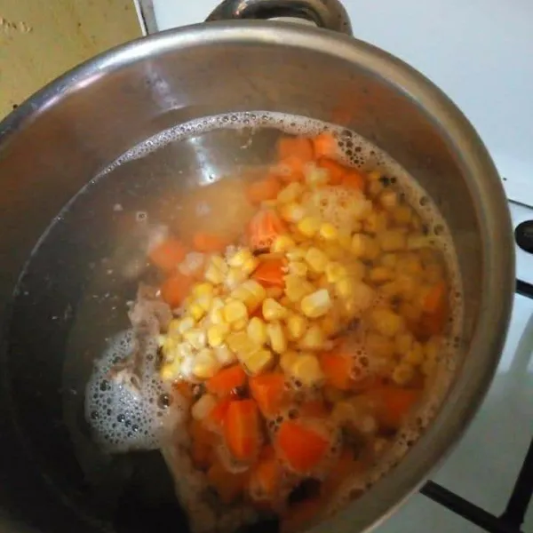 Siapkan air yang baru dalam panci didihkan, masukan potongan tulang, wortel dan jagung masak hingga sayuran setengah matang.
