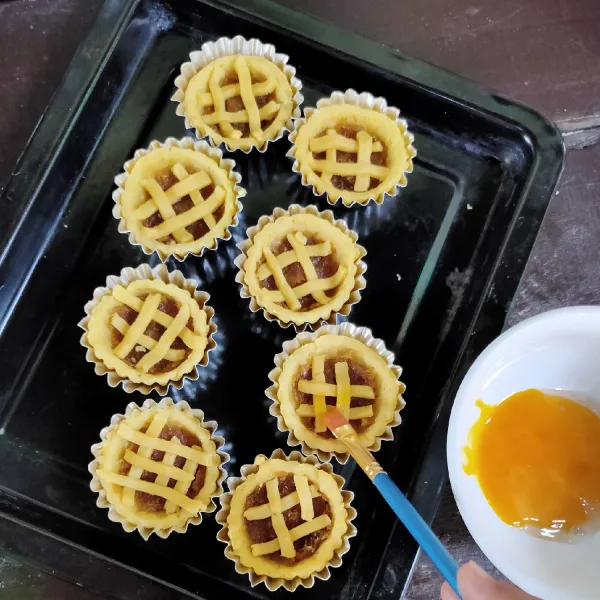 Buat pola anyaman diatas pie nanas, lalu oles merata dengan kuning telur.
