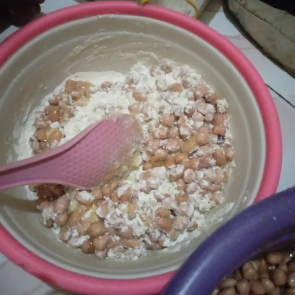 Ambil wadah lain. Kemudian sisihkan sedikit kacang tanah yang sudah diberi bumbu. Masukkan tepung sedikit demi sedikit.