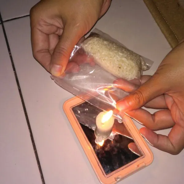 Rekat plastik berisi beras dengan api lilin.