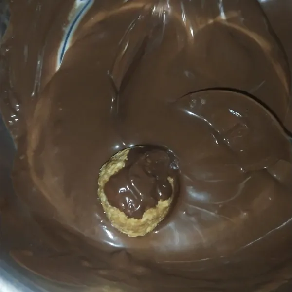 Masukkan bola regal ke dalam coklat, lumuri hingga semua permukaan bola regal penuh coklat.