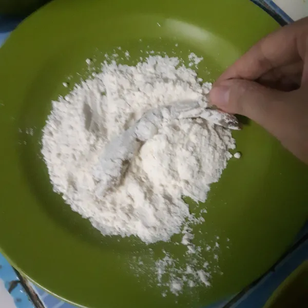 Siapkan tepung terigu di piring datar, baluri udang yang sudah di bumbui ke tepung terigu terlebih dahulu hingga rata.