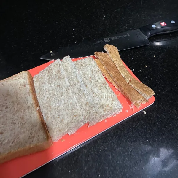 Potong pinggiran roti (agar ketika dipanggang dapat menjadi garing secara merata). Potong roti menjadi 2 bagian.