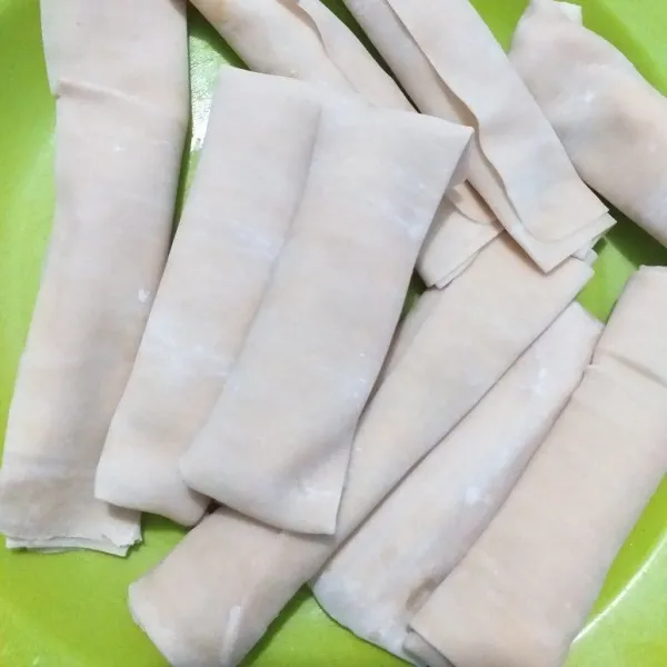 gulung-gulung kulit lumpia hingga tertutup rapi. larutan tepung terigu digunakan untuk menutup kulit lumpia