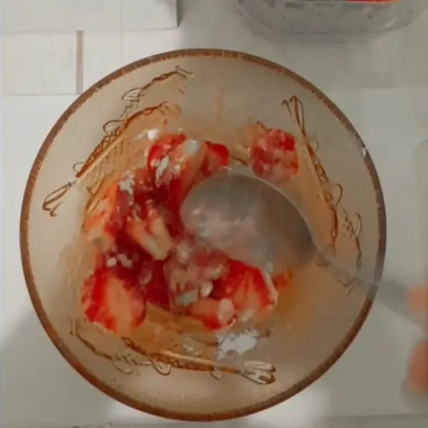 Masukkan irisan strawberry ke dalam gula halus, aduk aduk dengan sendok hingga berair.