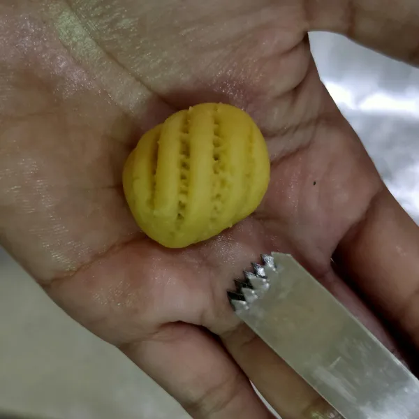 Ambil adonan tepung, isi dengan selai nanas, bentuk oval lalu jepit menyilang menggunakan penjepit nastar