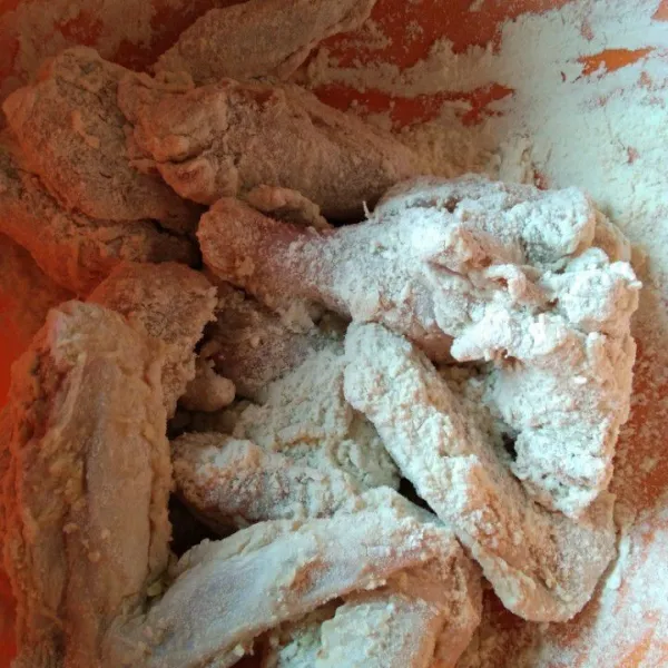 Tambahkan tepung terigu, aduk rata hingga tepung terigu nempel pada ayam.