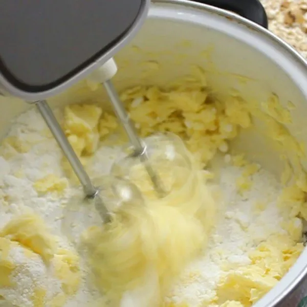 Mixer mentega, margarine, dan gula halus hingga memucat.