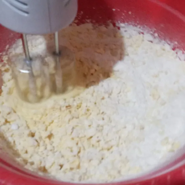 Tambahkan tepung terigu secara bertahap sampai semua tercampur rata, matikan mixer, lalu uleni sebentar.