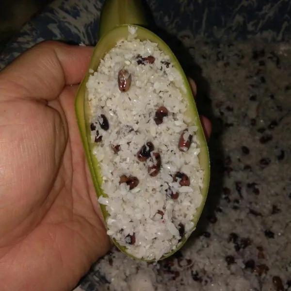 Gulung daun janur memanjang lalu isi dengan ketan.