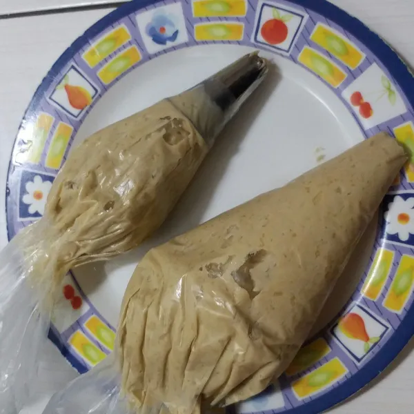 Masukkan adonan ke dalam plastik segitiga yang sudah di pasang spuit bintang.