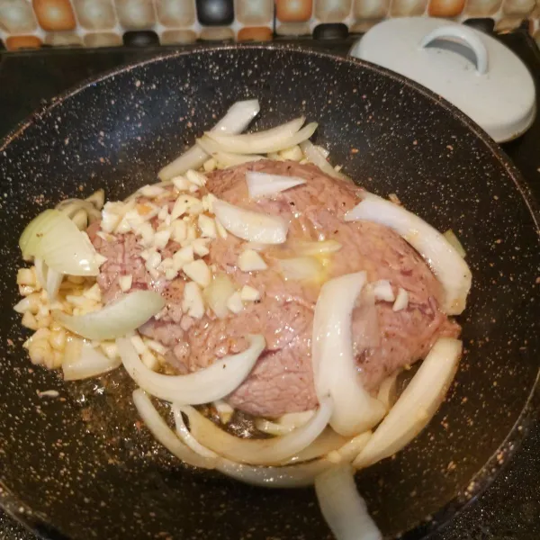 Letakkan daging masak sebentar lalu tambahkan potongan bawang putih cincang, bawang bombay dan baluri dengan salted butter diatas daging. seasoning lagi sesuai step 1.