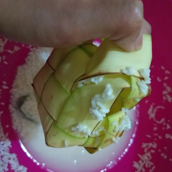 Ambil cangkang ketupat, masukan beras hingga 3/4 dari cangkangnya. Jika isi terlalu sedikit ketupat akan lembek, jika terlalu banyak akan menjadi keras.