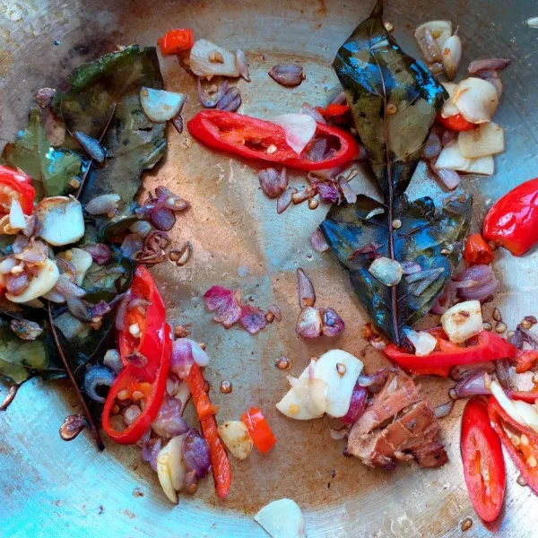 Tumis bumbu iris, lengkuas, daun salam hingga wangi dan layu.