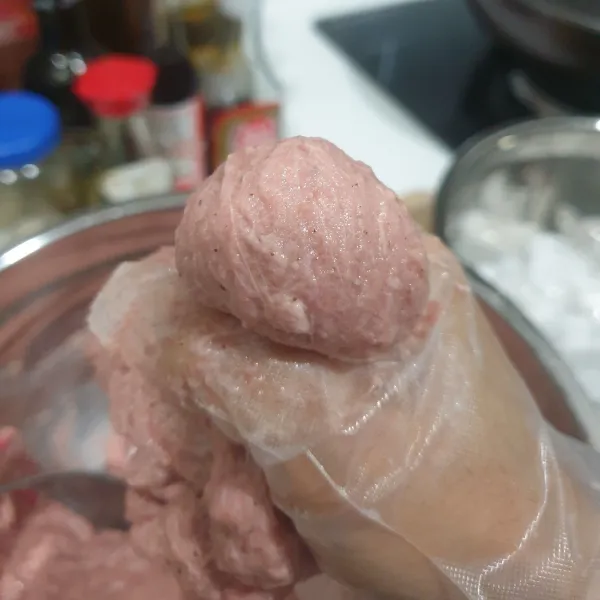 cetak bakso, dengan cara mengeluarkan adonan bakso dari sela-sela ibu jari dan telunjuk, Potong Bakso dengan punggung sendok.