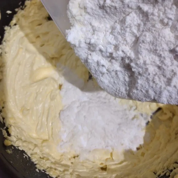 Masukkan campuran terigu ke dalam kocokan mentega sedikit demi sedikit sambil diaduk, hingga semua bahan tercampur.