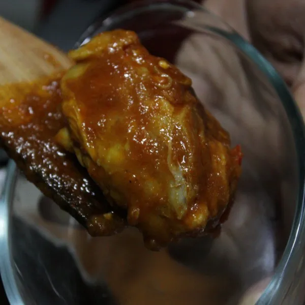 Matikan api, meletakkan satu persatu potongan ayam beserta bumbu ke dalam wadah anti panas.