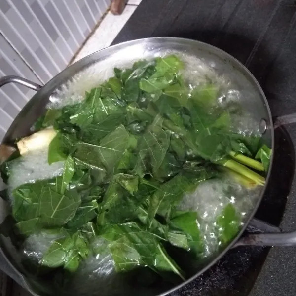 Didihkan air, masukkan sereh dan daun singkong, masak hingga setengah matang.