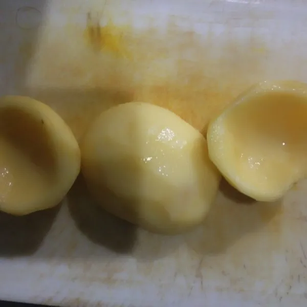 Potong kentang jadi dua bagian lalu kupas kulit kentang dan kerok bagian tengah kentang jadikan seperti mangkuk