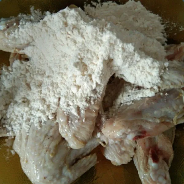 Tambahkan tepung terigu, aduk rata hingga tepung menempel semua pada sayap ayam.