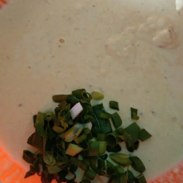 Tambahkan air aduk rata hingga kekentalan sedang, tambahkan irisan daun bawang.