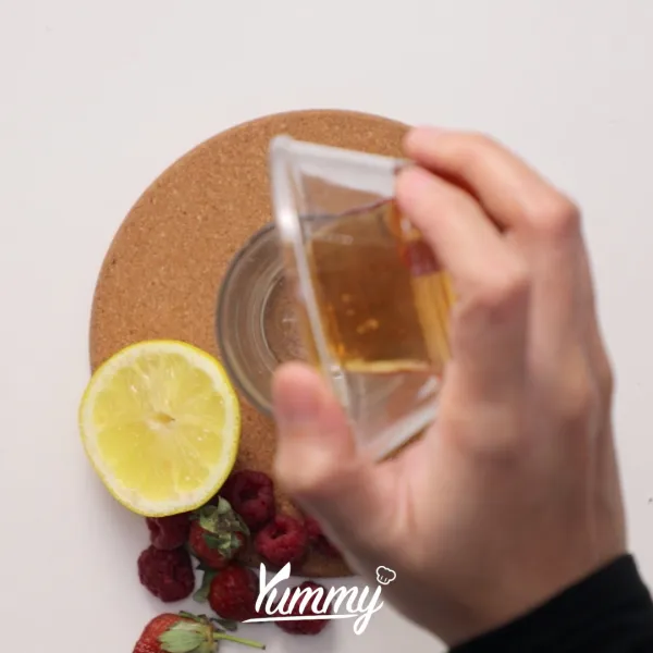 Siapkan gelas saji, tuangkan madu, ½ buah berries lainnya, dan lemon ke dalam gelas.