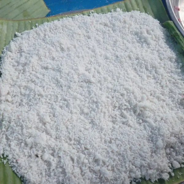 Siapkan tepung ketan lalu campurkan dengan gula pasir, aduk rata. Tata daun di atas loyang lalu masukan adonan separuh ratakan.