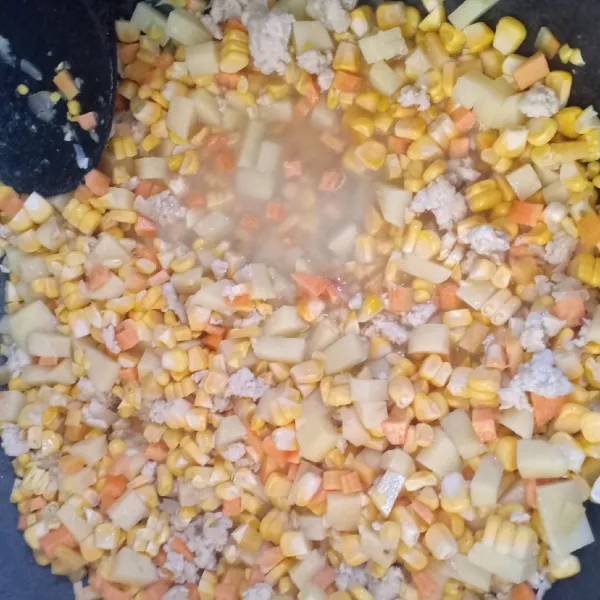 Masukkan jagung, kentang dan wortel lalu tambahkan air, masak hingga mulai matang, masukkan irisan daun bawang.
