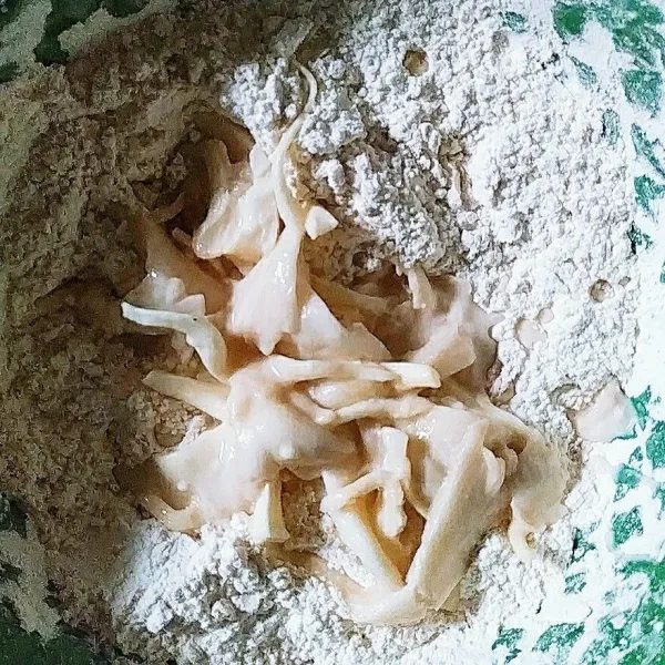 Lalu pindahkan jamur ke tepung kering dan aduk lagi hingga jamur terlumuri oleh tepung.