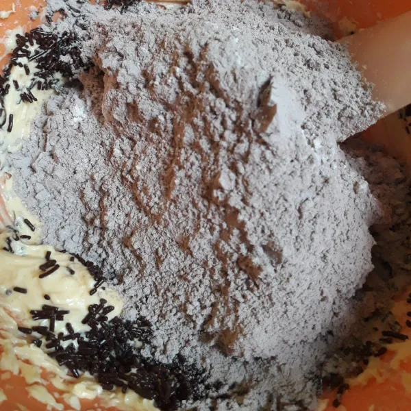 Tambahkan tepung terigu dan coklat bubuk yang telah diayak halus aduk rata dengan spatula.