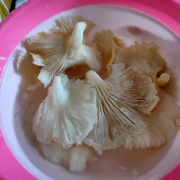 Cuci bersih jamur dengan air hangat, lalu peras airnya secara perlahan. Gulingkan dalam Tepung kering, satu persatu.