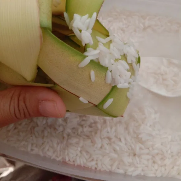 Isi selongsong ketupat dengan beras sampai setengah slonsong  atau lebih sedikit.