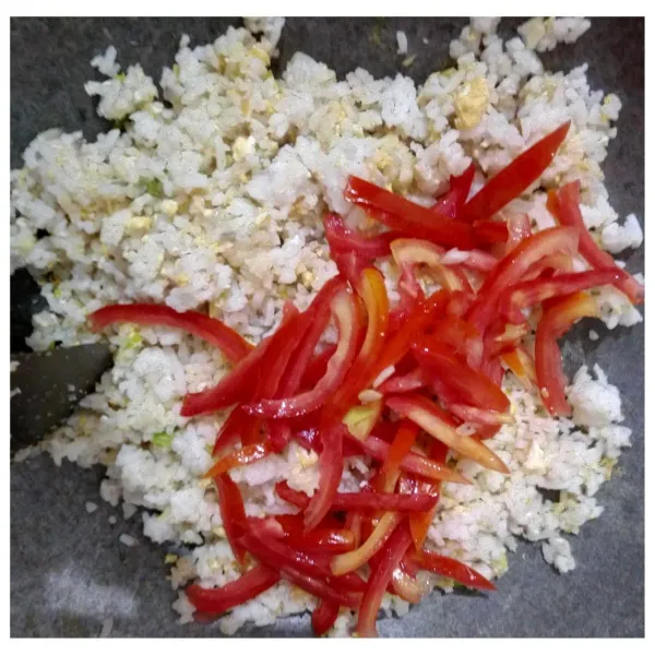 Masukkan irisan tomat kemudian aduk-aduk nasi hingga tomat matang dan menyatu dengan nasi (warna nasi berubah kemerahan alami).