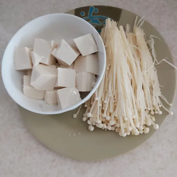 Cuci bersih jamur enoki suwir suwir jadi beberapa bagian, di sisi lain potong dadu tahu putih sutra.