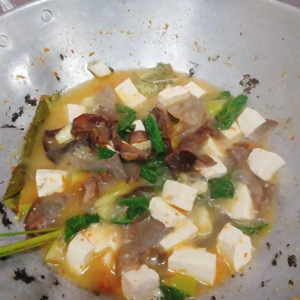 Setelah air mendidih masukkan sayuran dan tahu serta tambahkan garam dan penyedap rasa, lalu koreksi rasa.