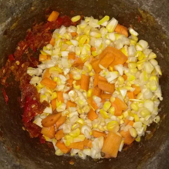 Masukkan jagung dan wortel, lalu ditumbuk bersamaan dengan bumbu halus.