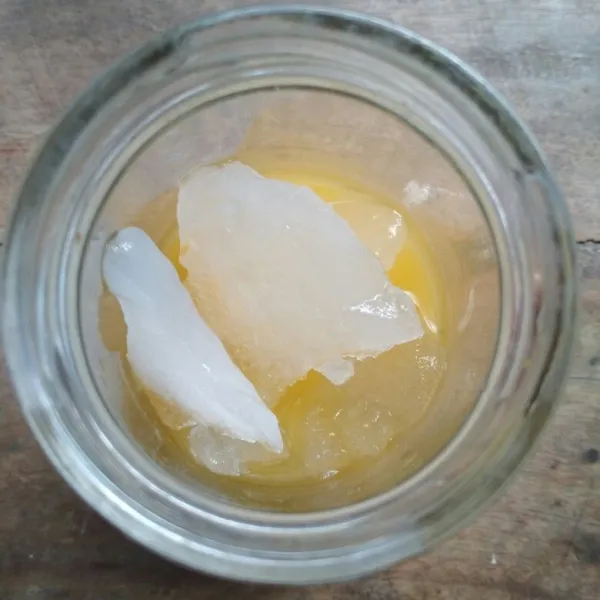 Dalam gelas saji tuang larutan Nutrisari markisa dan es batu.