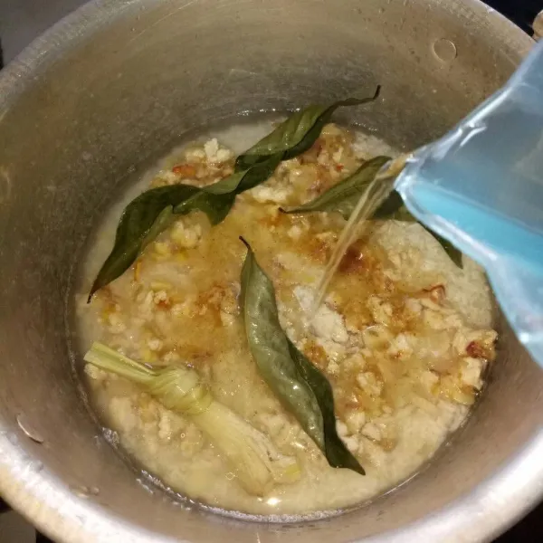 Cuci bersih beras dan tiriskan. Siapkan panci, kemudian masukkan beras, tumisan ayam, garam, kaldu bubuk dan air. Setelah itu aduk rata dan masak dengan api sedang.