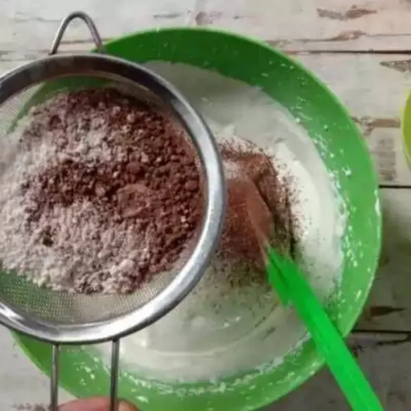 Masukkan tepung terigu dan coklat bubuk sambil diayak. Aduk balik sampai rata.