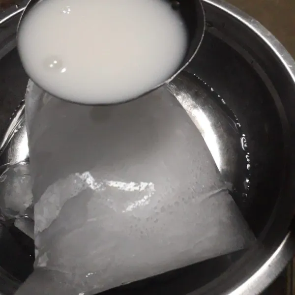 Siapkan wadah besar dengan 1 bongkah es batu dan sedikit air matang,tuang perlahan satu sendok sayur ke permukaan es batu.