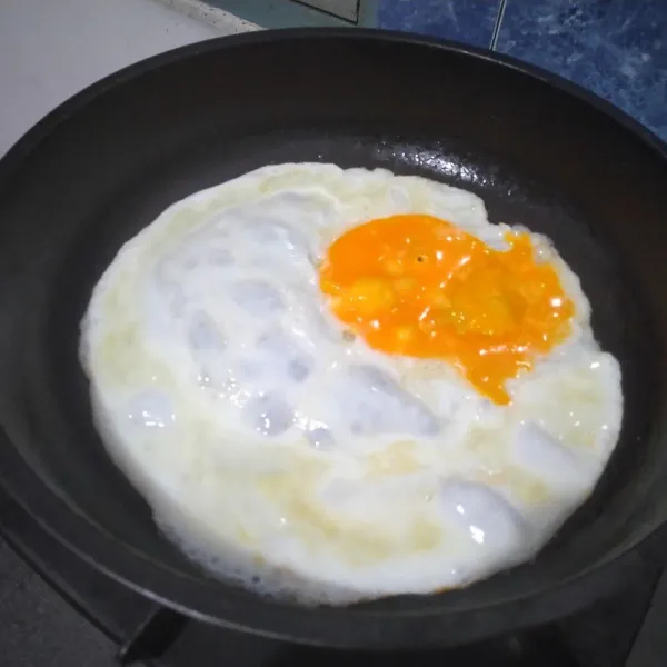 Panaskan teflon. Kemudian buat telur mata sapi dengan kuning di pinggir pada satu bagian.