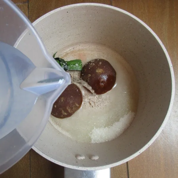 Masukkan gula merah, gula pasir, garam dan daun pandan dalam panci. Tuang air.
