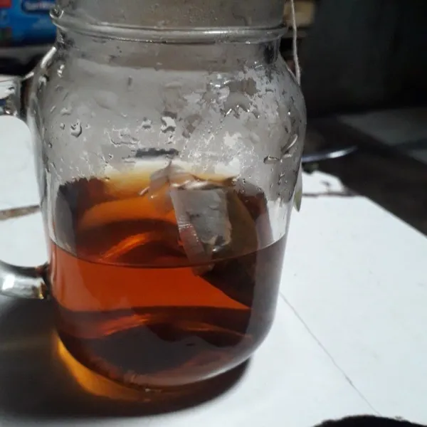 Tuang air panas dan teh celup ke dalam gelas.