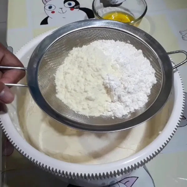 Tambahkan tepung terigu, maizena, susu bubuk, dan garam sambil diayak. Kemudian aduk balik dengan spatula hingga rata.