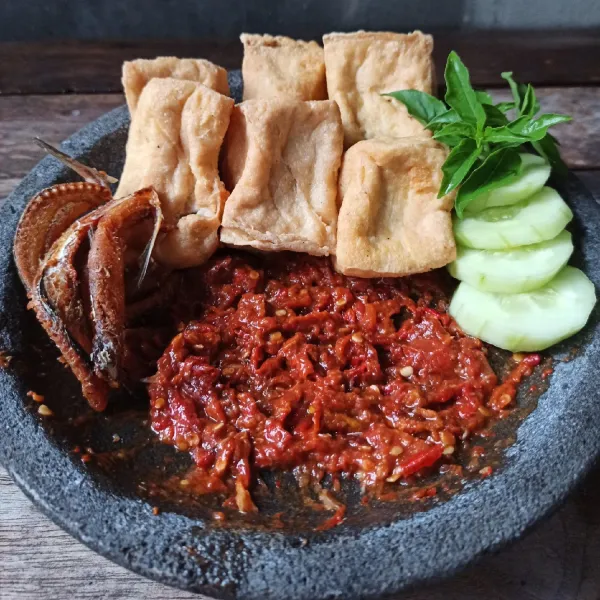 Susun ikan asin, tahu, kemangi dan timun di atas cobek, sajikan dengan nasi hangat.