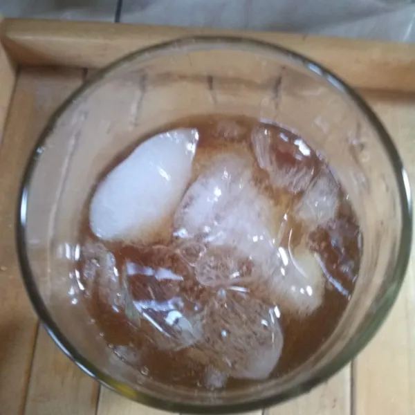 Dalam gelasain tambahkan es batu, kemudian teh yang sudah diseduh.