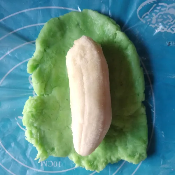 Ambil 2 sdm adonan, pipihkan, lalu beri pisang di tengah-tengah.