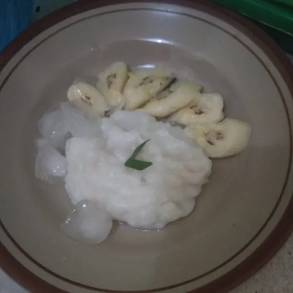 Ambil beberapa sendok bubur beras, beri potongan pisang. Siram dengan sirup cocopandan, kental manis putih dan es batu.
