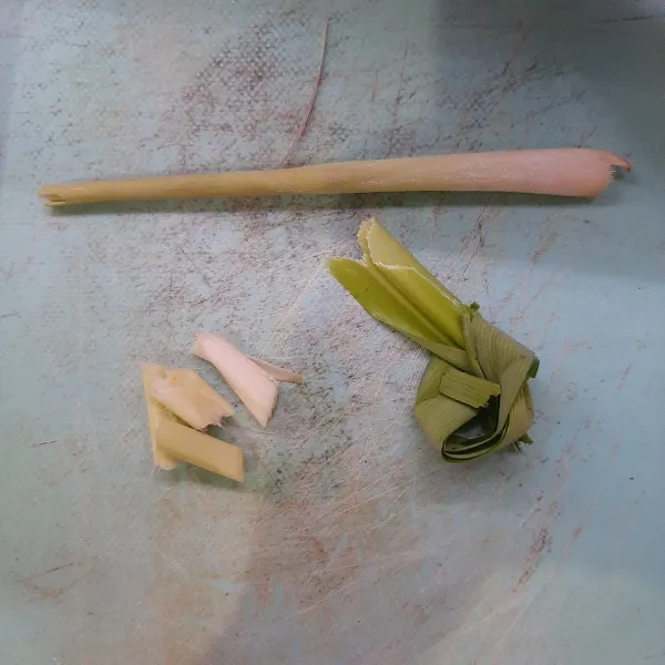 Siapkan bahan: robek sebagian pandan dan buat simpul pita. Ambil sebagian ujung sereh bagian putihnya, potong-potong dan geprek sedikit, sisa sereh sisihkan untuk hiasan.